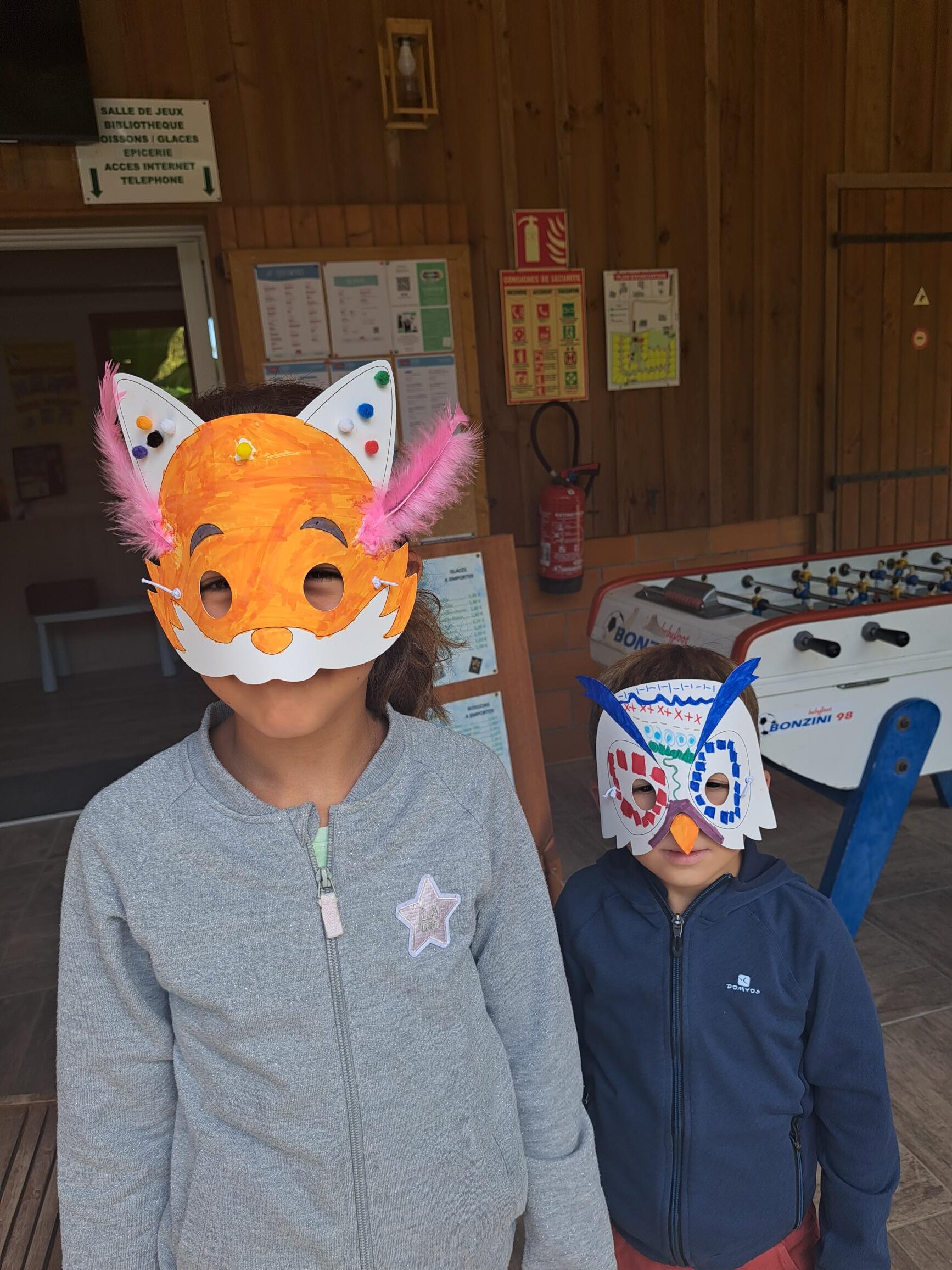 Enfants portant des masques de renard et d'oiseau faits main lors d'une activité créative de vacances.
